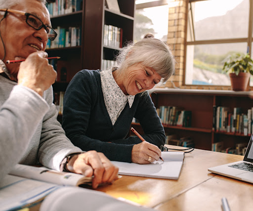 Senior couple taking notes in a library for their life long learning program