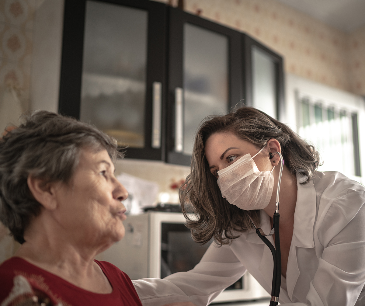Female caregiver helping patient while wearing mask