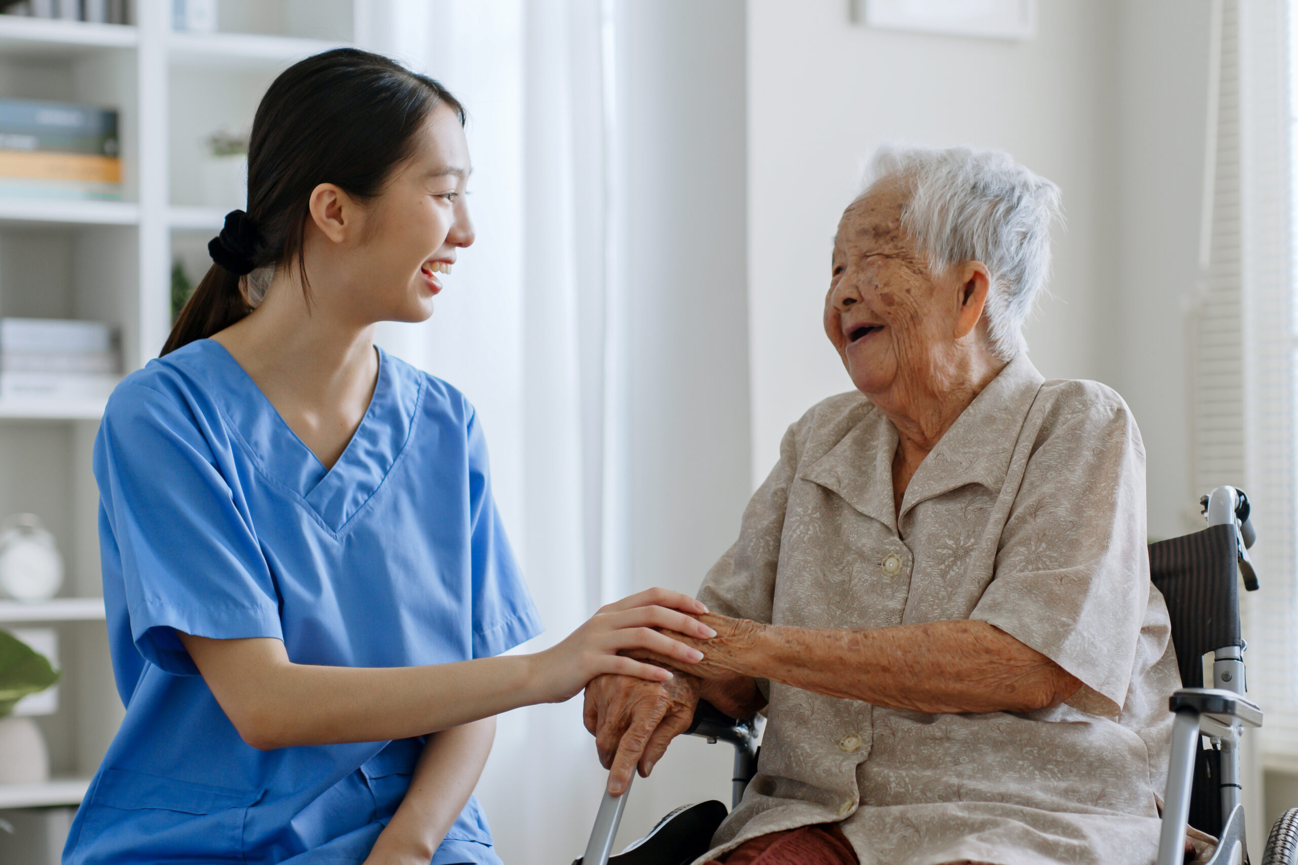 Young Asian woman, nurse, caregiver, carer of nursing home talking with senior Asian woman feeling happy at home