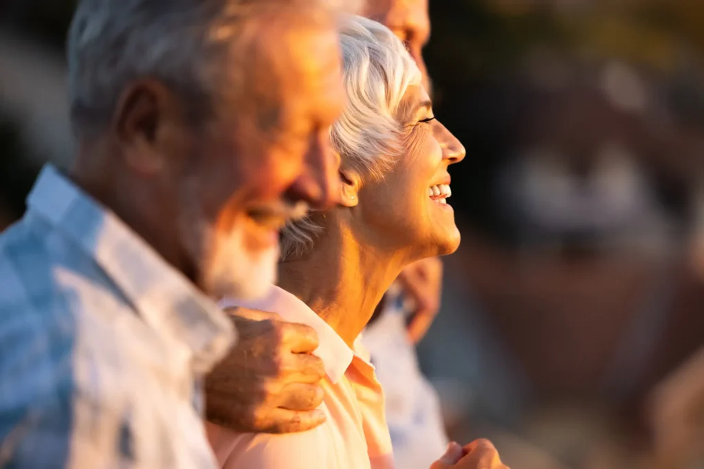 A side picture of happy, social, independent seniors at Sagewood with a reflection of the sun in their face.