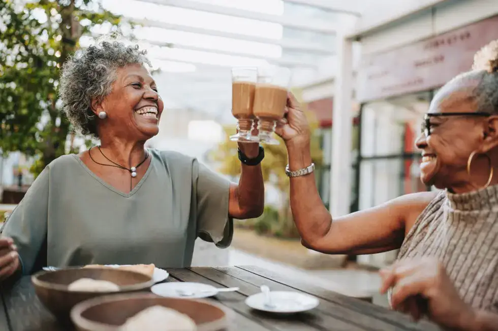 two senior women toasting coffee while figuring out the best places to retire in Arizona. Sagewood in Phoenix is a great choice.