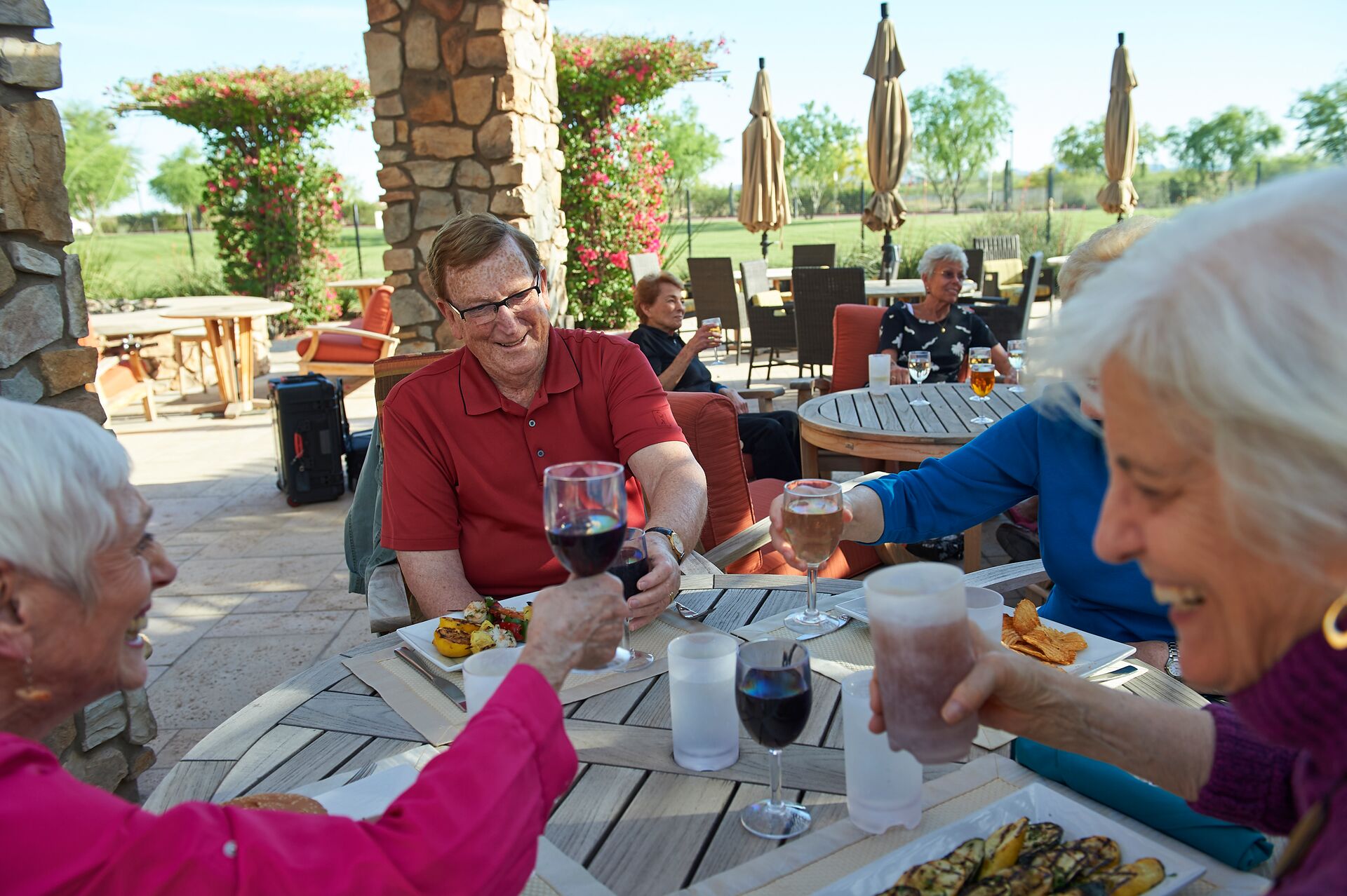 A group of seniors enjoy dining outdoors.